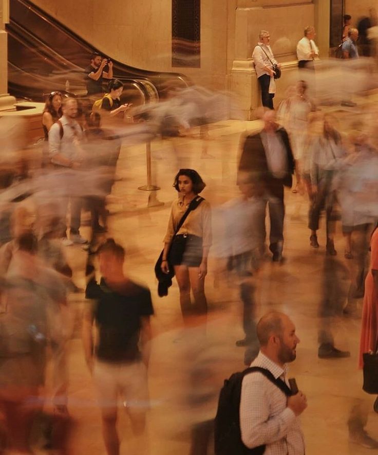 A still figure surrounded by people moving through a busy public space